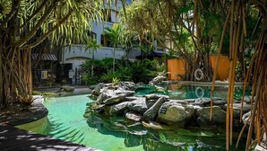 A clear pool with rocks and a wooden deck. - Luxurious Resort Apartment with 9 Pools and Patio (Westcourt)