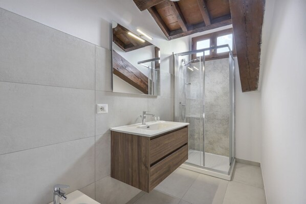 A modern bathroom with a wooden vanity, a glass shower enclosure, and a large mirror. - Palazzo Borghese Studio Terravce (Firenze)