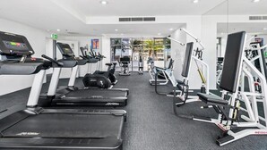 Un gimnasio con cintas de correr, elípticas y equipo de levantamiento de pesas.
