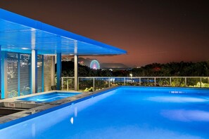 Un espace piscine moderne doté d’un coin salon abrité, d’où l’on peut admirer une grande roue et, au loin, une chaîne de montagnes.