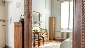 A room with a large wooden-framed mirror reflecting a dining area, a radiator, and a door.