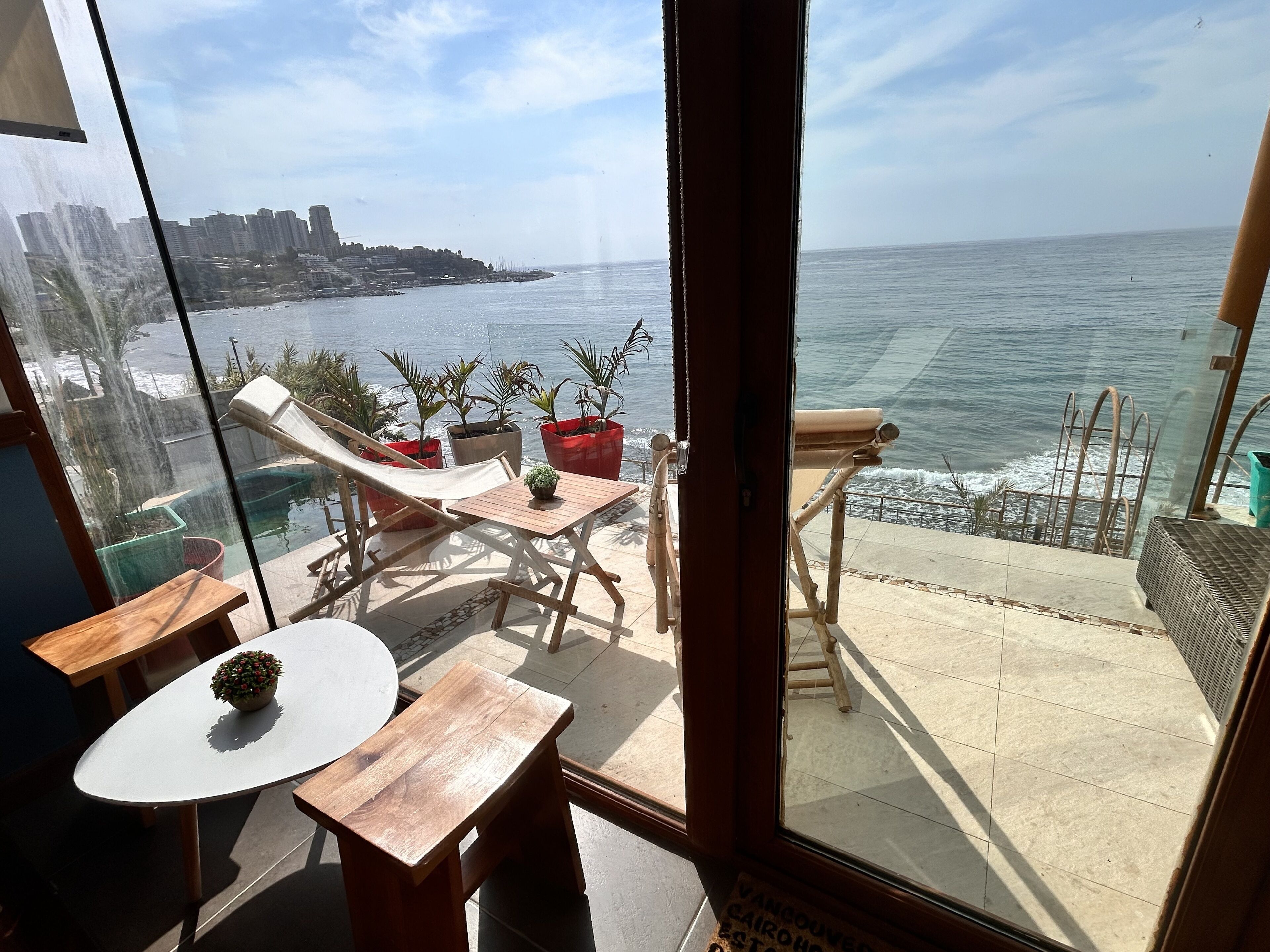 Uma varanda com vista para o oceano, móveis de madeira e plantas em vasos.