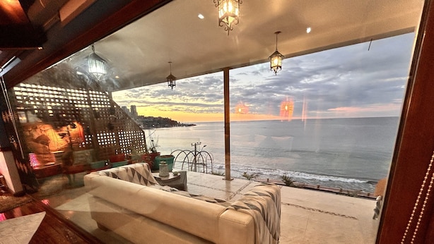 A modern living room with a large sofa, a small table, and a view of the ocean. - PACIFICSUNSET CONCÓN (Concon)
