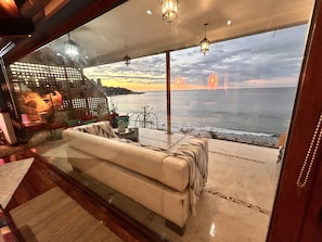 A modern living room with a large sofa, a small table, and a view of the ocean. - PACIFICSUNSET CONCÓN (Concon)