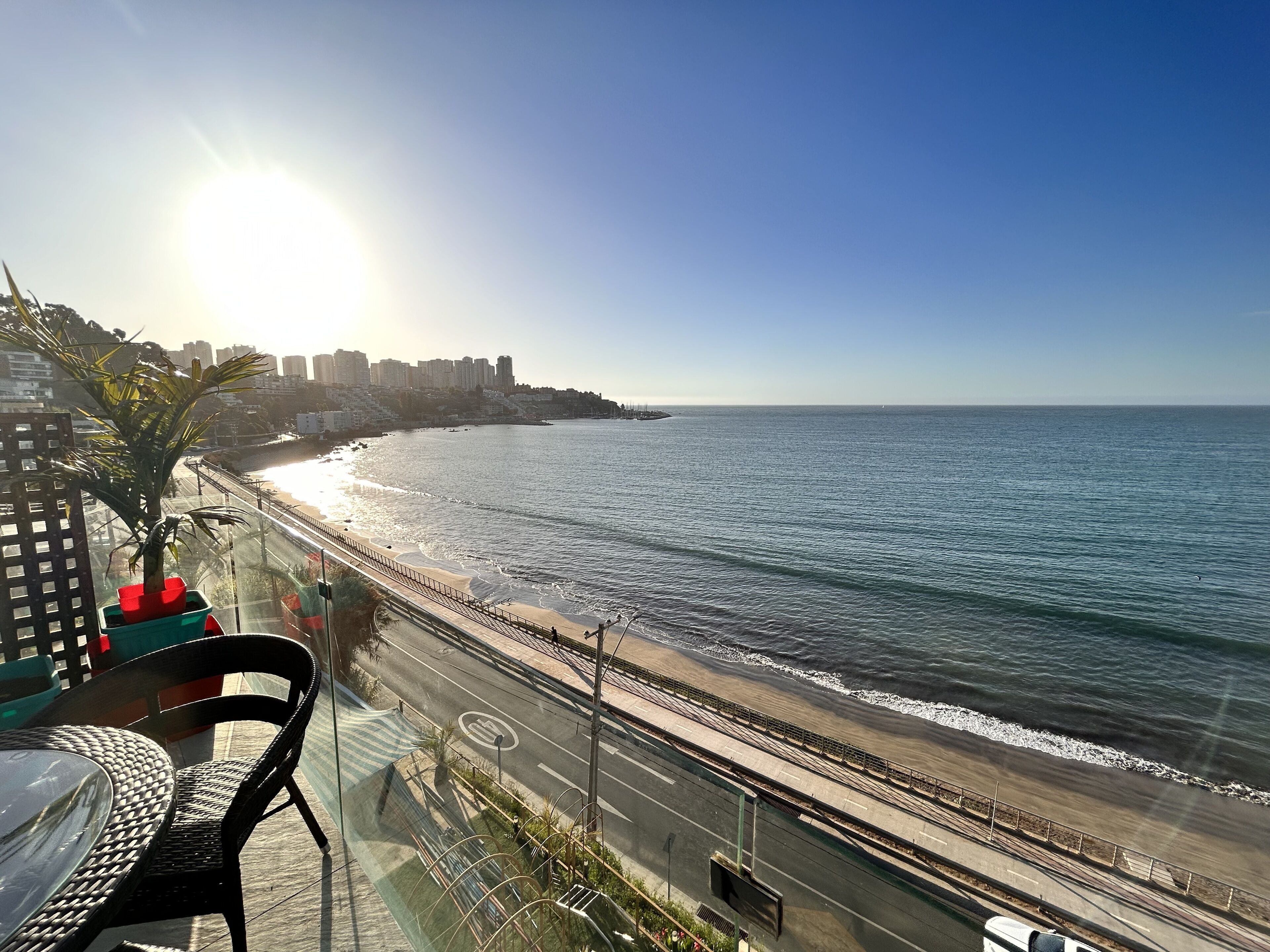 A coastal road with a beach on one side and a cityscape on the other.