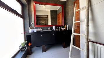 A modern bathroom with a black vanity, a large mirror, and a wooden door.