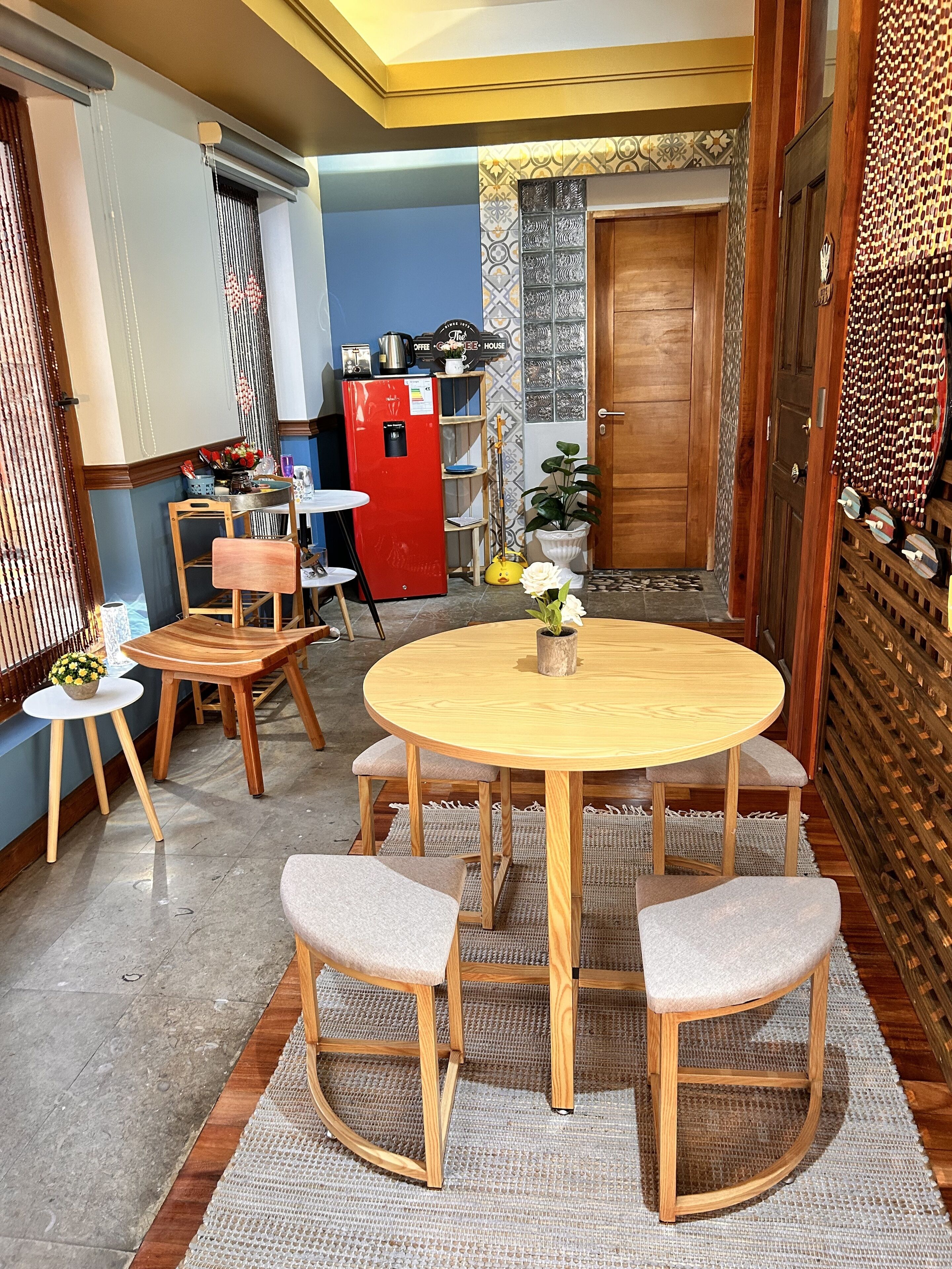 A dining area with a round wooden table and four chairs, a red refrigerator, and a wooden cabinet.