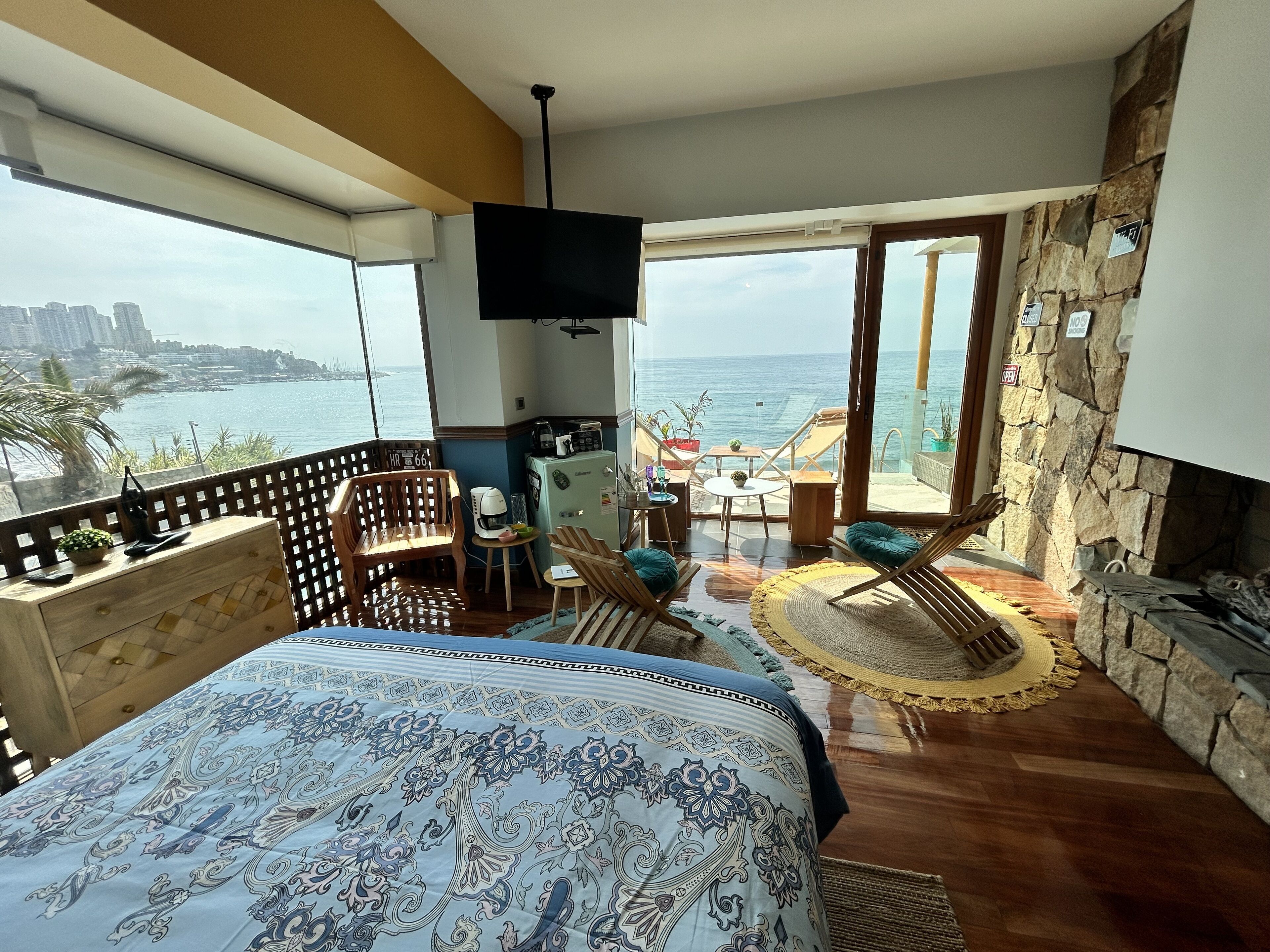 Un balcon avec vue sur la mer, un lit avec une literie à motifs et un coin cuisine.