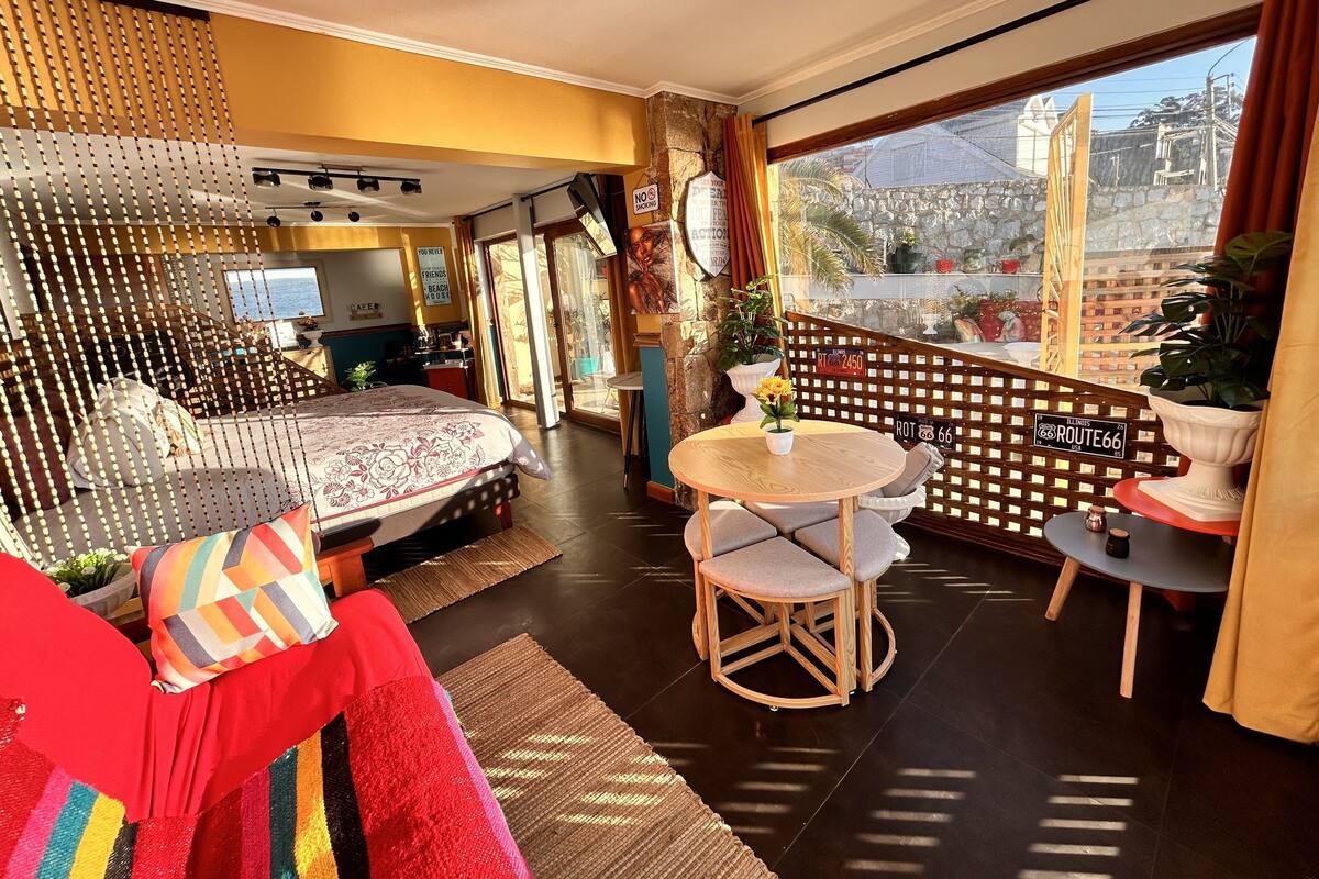 A hotel room with a bed, a dining table, and a balcony with a view.
