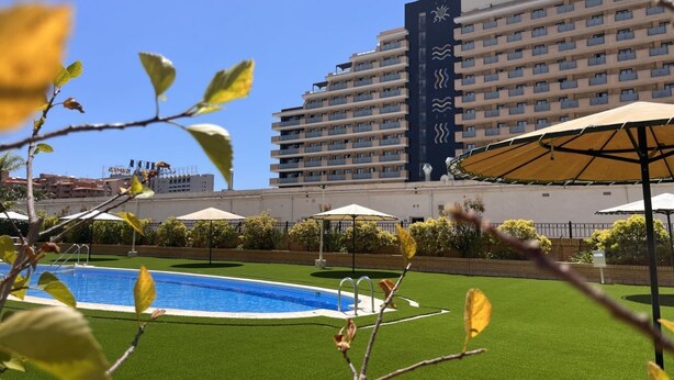A hotel with a swimming pool, outdoor umbrellas, and a large building with a sports theme. - This charming flat offers spacious and relaxing views of the pool and beach, providing an unrivalled holiday experience. Situated second line, it is only about 300 metres from the beach and in close proximity to parks, the spa, a variety of restaurants a (OROPESA)