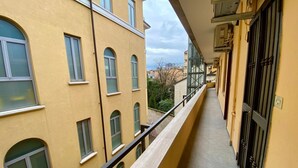 Un estrecho pasillo con balcones, paredes amarillas y numerosas ventanas.