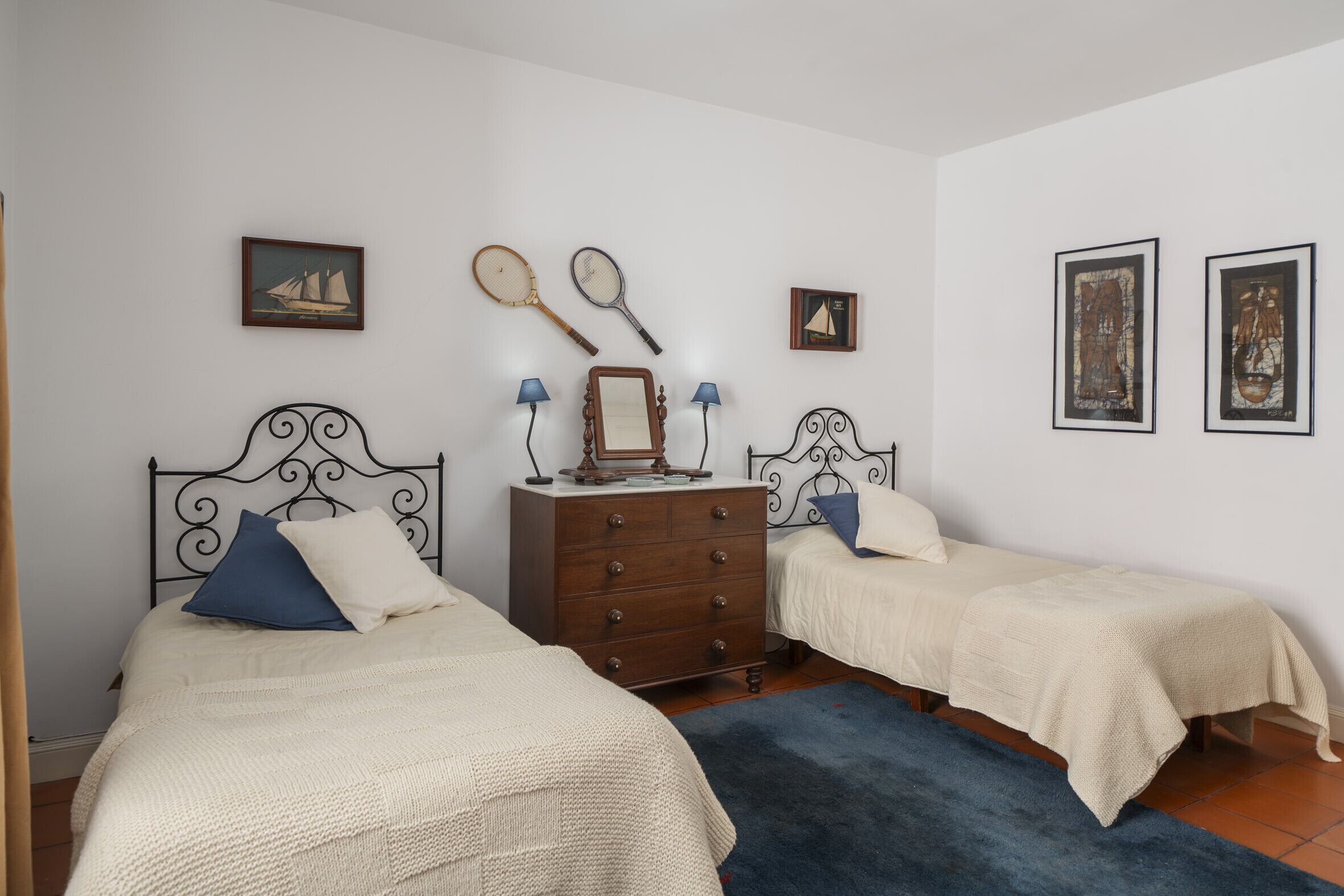Quarto com duas camas, penteadeira e luminárias fixadas na parede.