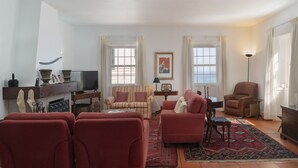 Ein Wohnzimmer mit roten Sofas, einem Fernseher, einem Kamin und einem gemusterten Teppich.