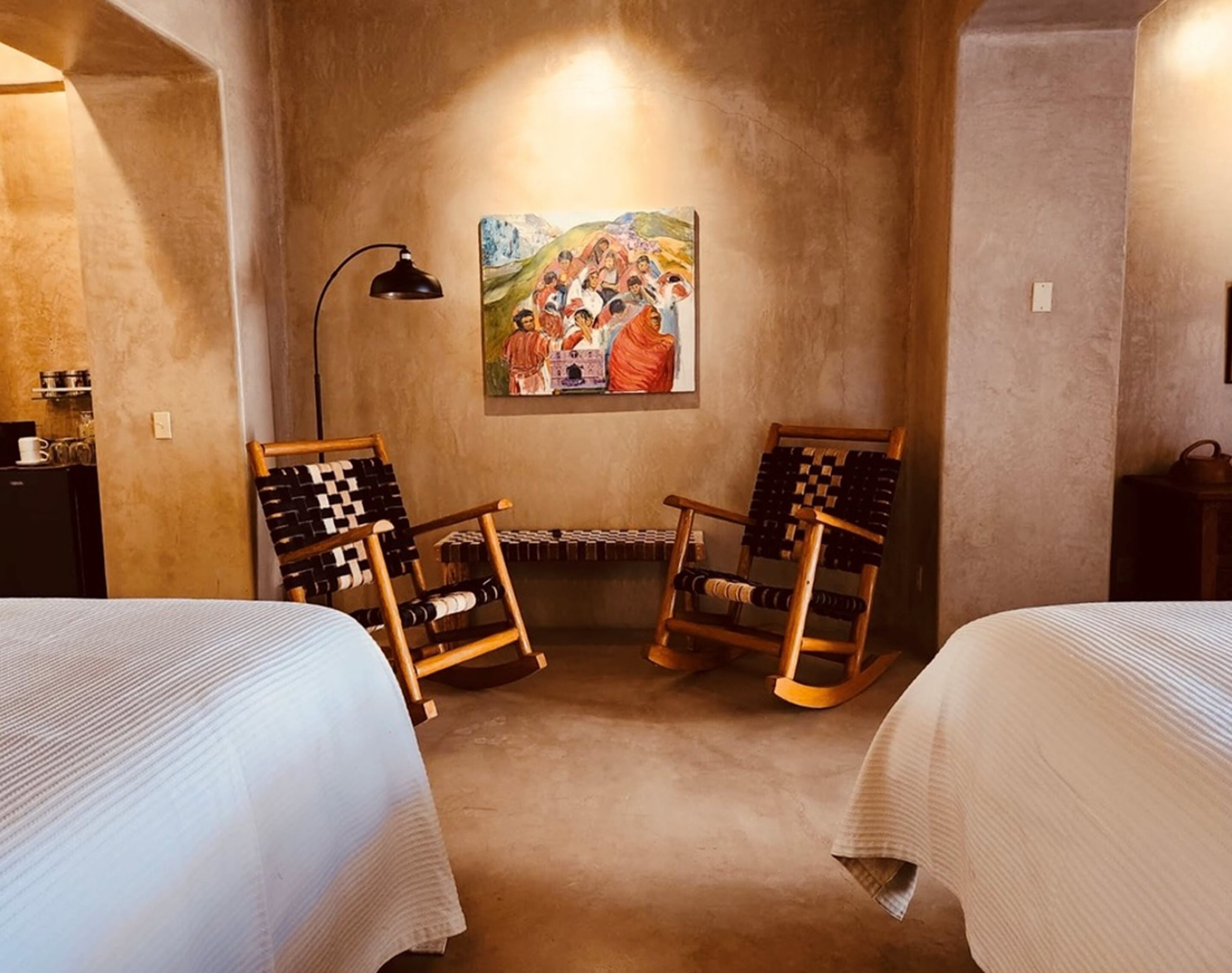 A cozy room with two wooden rocking chairs, a painting on the wall, and a lamp.