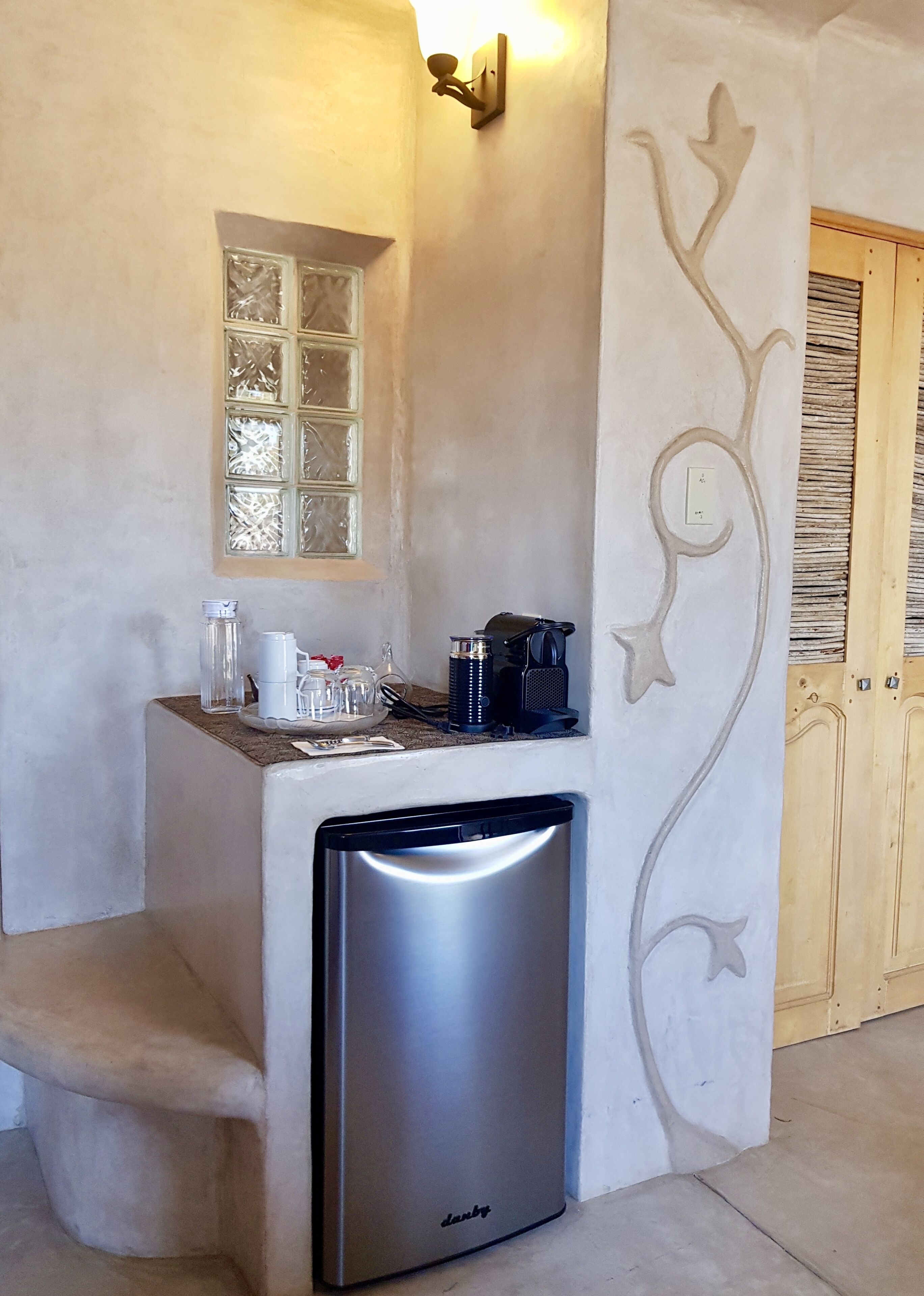 A compact kitchenette with a built-in dishwasher, a small window, and a decorative wall design.
