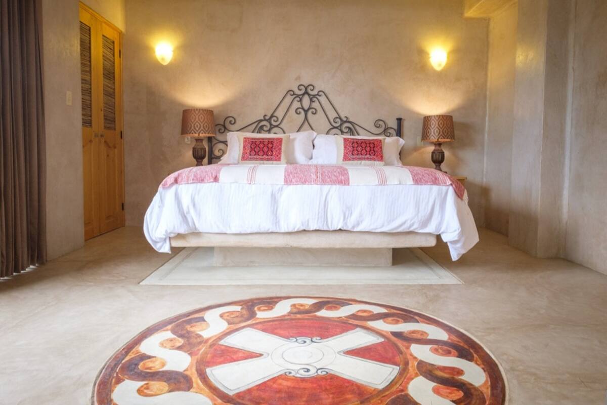 Een slaapkamer met een bed, twee wandlampen, een houten deur en een vloer met een patroon.