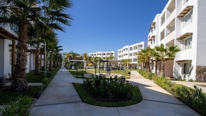 A hotel courtyard with a central garden, palm trees, and a pathway leading to the building. - Almarena Apartments Coto Coral (Mazatlán)