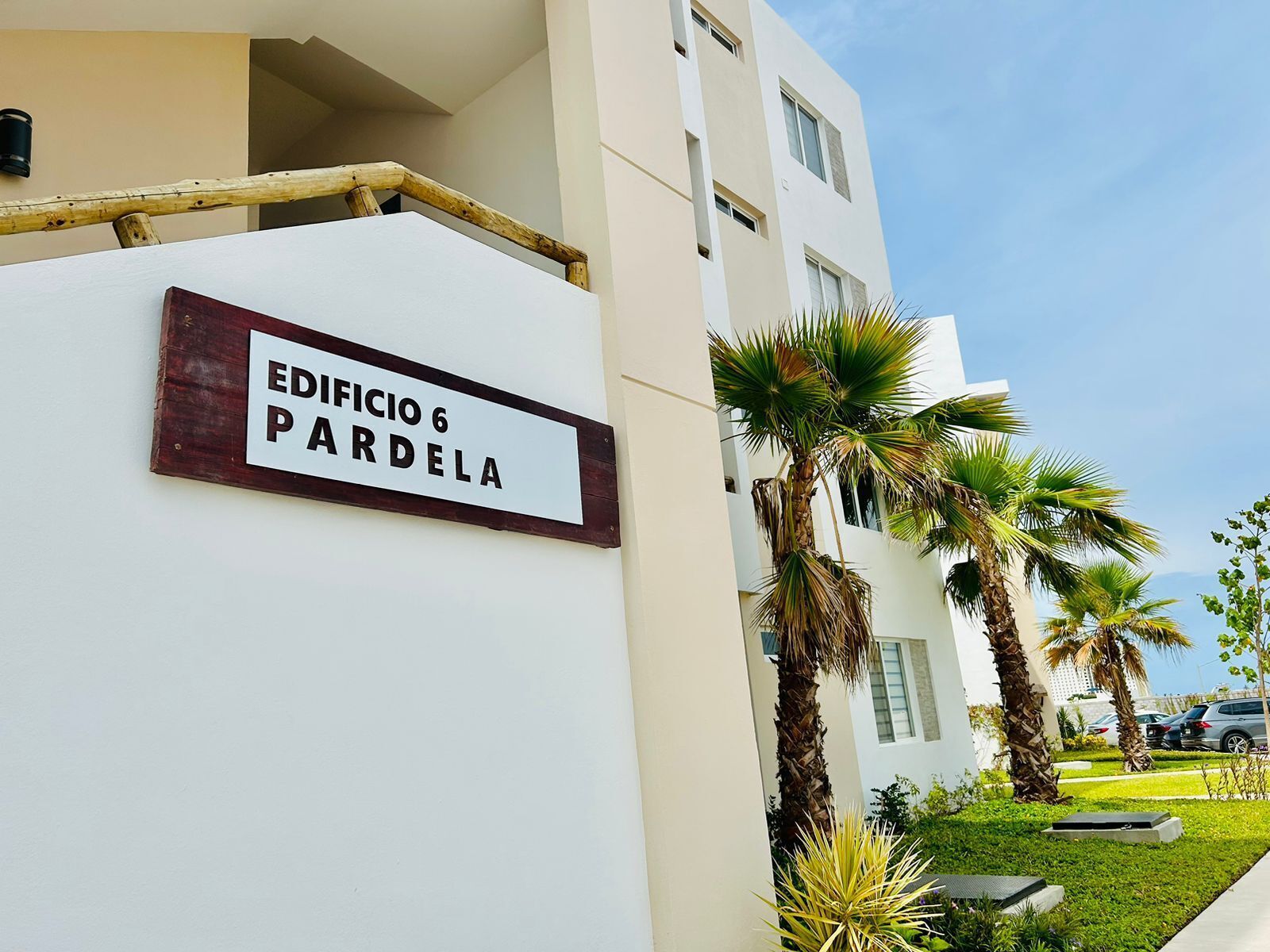 A building with a sign reading "EDIFICIO 6 PARDELA" and palm trees in the foreground.