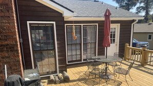 En terrasse med bord og stole, grill og en overdækket parasol.