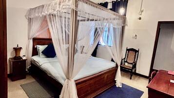 Un dormitorio con cama de dosel, ventilador de techo y mesita de noche con lámpara.