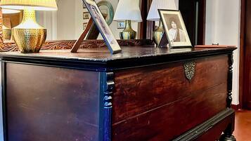 A dark wooden dresser with ornate carvings, a mirror above it, and three lamps on the dresser.