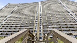 A high-rise building with a grid-like facade, multiple balconies, and a central stairwell.