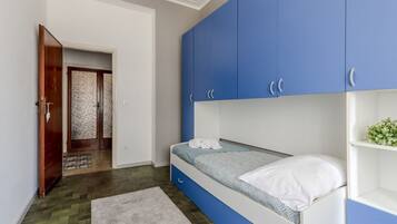 Un dormitorio con cama, armario azul y puerta de madera.