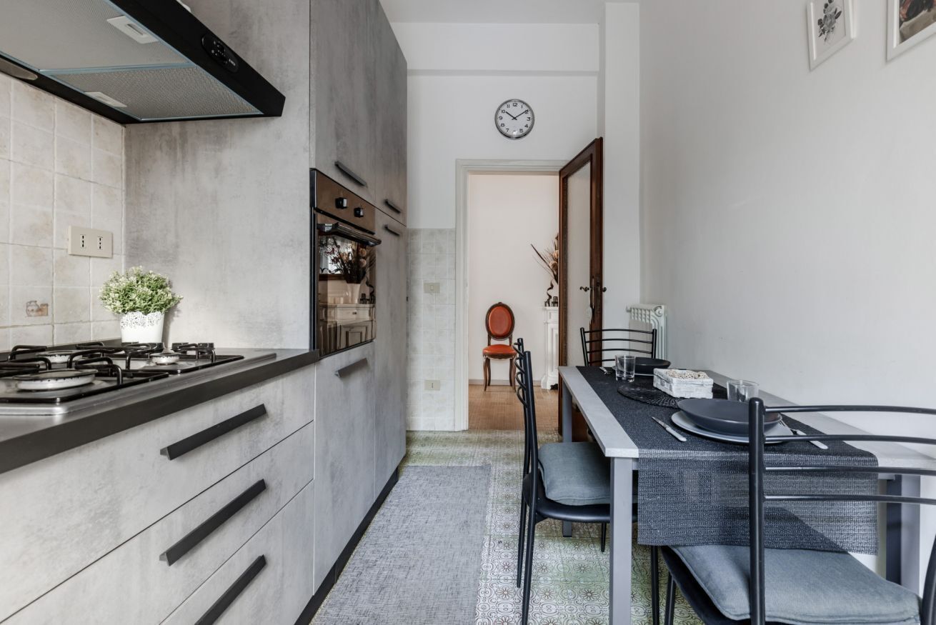 A modern kitchen with a gas stove, cabinets, and a dining area with a table and chairs.