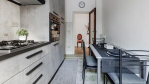 Una cocina moderna con estufa a gas, armarios y un comedor con mesa y sillas.