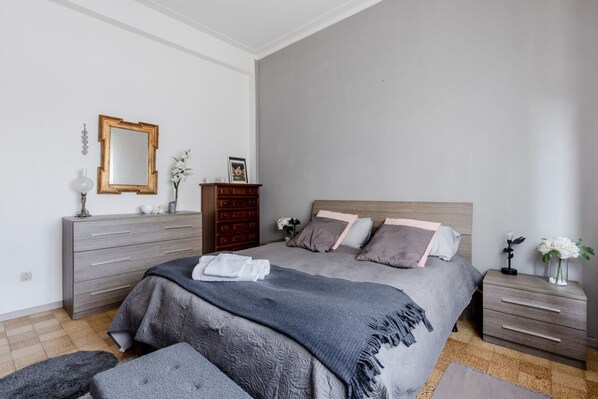 A bedroom with a bed, a dresser, a nightstand, and a mirror.