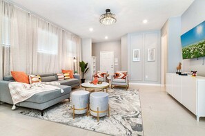 A modern living room with a grey sofa, armchairs, a coffee table, and a TV. - 5 En-Suites | Free Access to Amazing Resort! (Davenport)