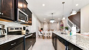 A modern kitchen with dark cabinetry, stainless steel appliances, and a central island.
