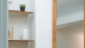 Une pièce avec un meuble en bois, des étagères ornées d’objets décoratifs, un miroir et un téléviseur à l’arrière-plan.