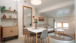 Un espace repas moderne avec une table blanche, des chaises en bois et un tapis rond.