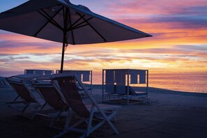 Beach chairs and umbrellas on a sandy beach with a sunset in the background. - Incredible Junior Suite Ocean View at Garza Blanca 5-Star Resort: Los Cabos (Cabo San Lucas)