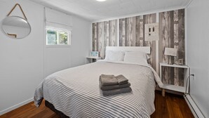 Une chambre à coucher avec un grand lit, une table de chevet avec une lampe, un miroir et une fenêtre.