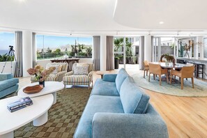 A modern living room with a sofa, armchairs, a coffee table, and a dining area with chairs and a table. - Stunning apartment - 211 with views of Bondi Beach (Bondi)