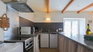 Una cocina compacta con electrodomésticos modernos, horno integrado, microondas y lavavajillas.