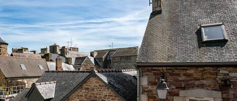A stone building with a sloped roof, a small window, and a street lamp.
