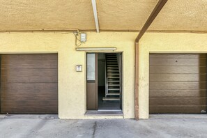 A building with two closed garage doors, a set of stairs leading to an entrance, and a utility box on the wall. - Apartment 'La Siesta' with Private Terrace and Wi-Fi (L'Escala)