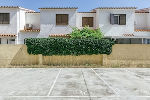 A building with white walls, brown tiled roofs, and a green hedge.