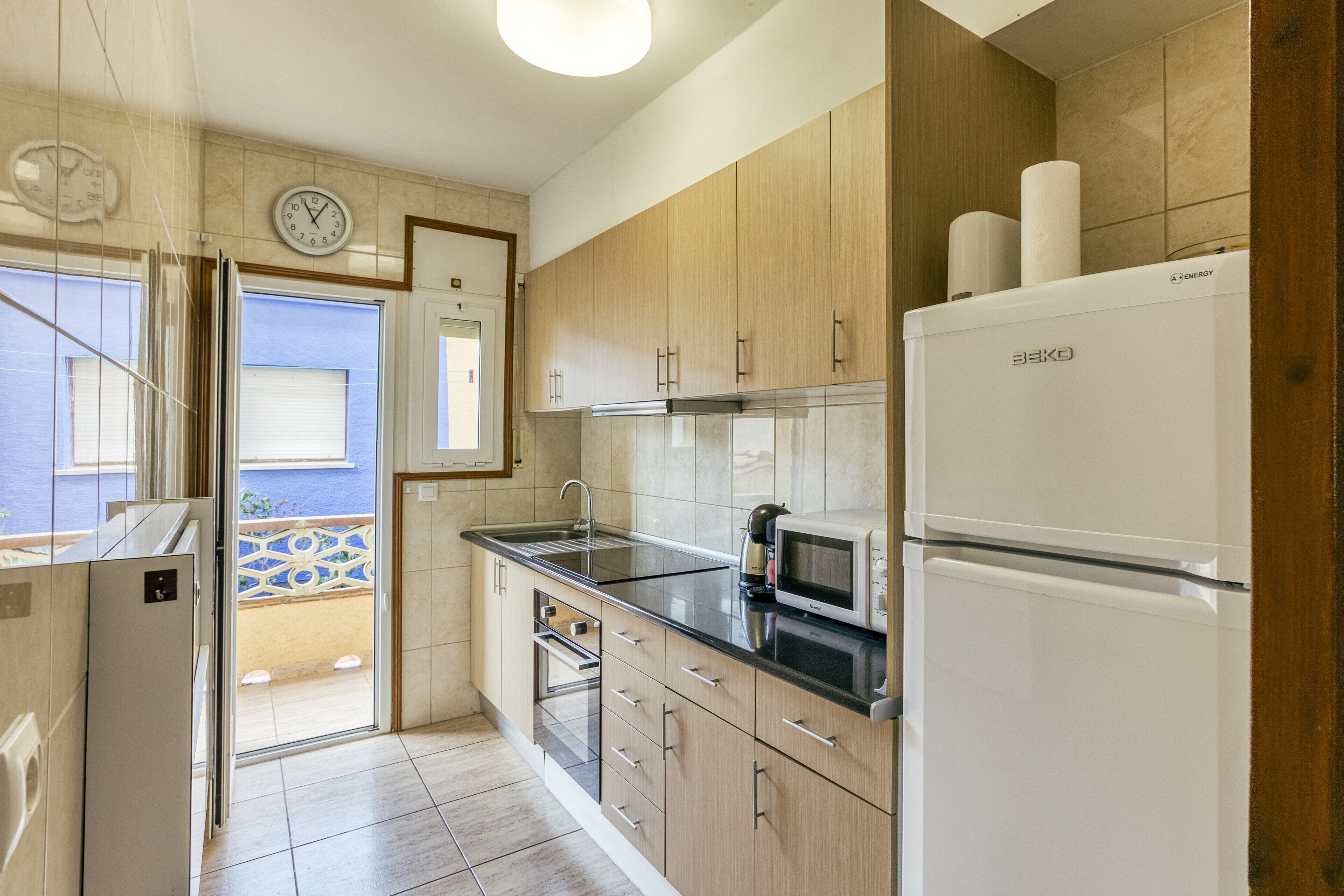 A modern kitchen with wooden cabinets, a refrigerator, a microwave, and a sink.