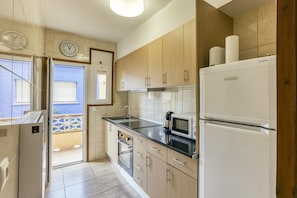 A modern kitchen with wooden cabinets, a refrigerator, a microwave, and a sink.
