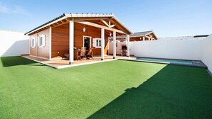 Ein Holzhaus mit überdachter Terrasse und Swimmingpool.
