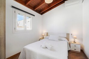 Hotellihuone, jossa on sänky, kaksi yöpöytää, ikkuna ja kattotuuletin.