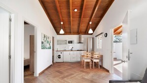 Eine geräumige Küche mit Holzboden, einem Essbereich mit Stühlen und einer hohen Decke mit freiliegenden Balken.