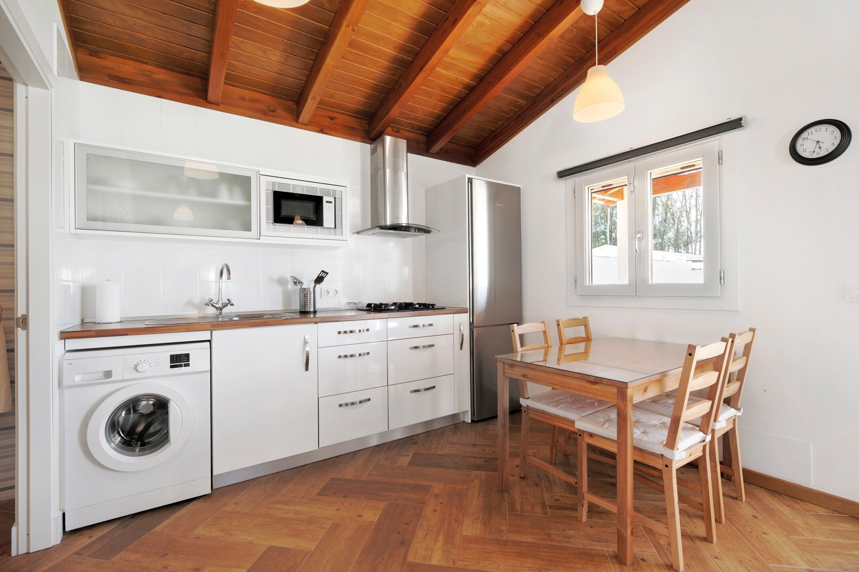 A kitchen with a washing machine, microwave, stove, and refrigerator.
