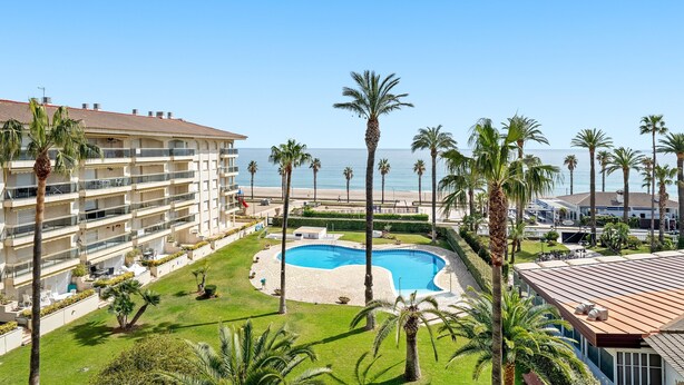 Ein Resort mit Swimmingpool, Palmen und Blick auf den Strand.