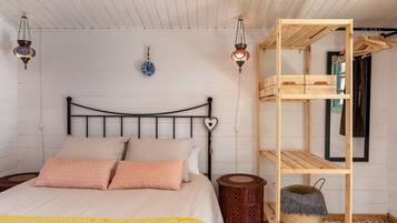 Una cama con cabecera, una estantería de madera y dos faroles colgantes.