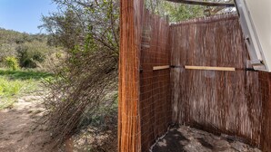 Een omheining van bamboe met een houten poort, omringd door natuurlijke begroeiing.